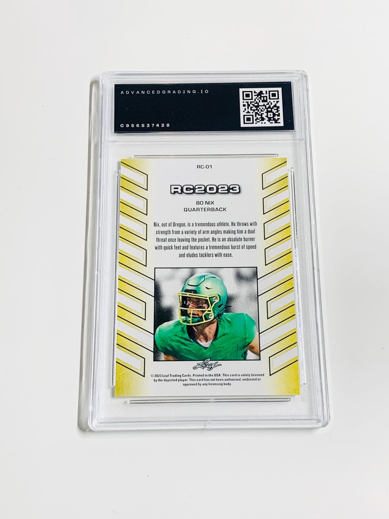 K&ouml;nnte beinhalten: Eine bewertete RC2023 Bo Nix Quarterback Trading Card. Die Karte zeigt ein Foto des Spielers in einem gr&uuml;nen Helm und Uniform. Die Karte ist in einem transparenten Kunststoffhalter mit dem Text "ADVANCEDGRADING.IO" oben eingeschlossen.