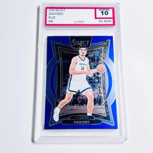 May include: A blue basketball trading card featuring Zach Edey in a Grizzlies uniform. The card is graded Pristine 10 and encased in a clear protective holder. The card's details include "2024 Select," "Zach Edey," and "#98."