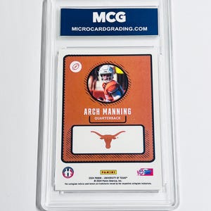 K&ouml;nnte beinhalten: Eine bewertete 2024 Panini University of Texas Arch Manning Football-Karte in einer durchsichtigen Kunststoffh&uuml;lle. Die Karte hat einen orangefarbenen Hintergrund, ein kreisf&ouml;rmiges Foto des Quarterbacks, den Text Arch Manning und ein Longhorn-Logo.