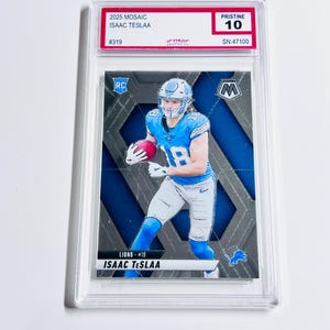 May include: A graded sports trading card featuring Isaac Teslaa of the Lions. The card has a mosaic design with blue and silver accents. The card is encased in a protective holder and is graded Pristine 10.