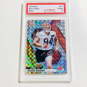 Op de afbeelding: Een 2025 Mosaic voetbal trading card met Mason Graham van de Browns, beoordeeld als Pristine 10. De kaart heeft een moza&iuml;ekontwerp met een speler afbeelding in een wit uniform en het nummer 94. De kaart zit in een doorzichtige beschermhoes.
