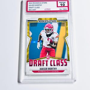 May include: A sports trading card featuring Xavier Worthy in a Kansas City Chiefs uniform. The card is labeled "2024 Rookies & Stars Draft Class" and is graded "Pristine 10". The card is encased in a clear protective holder.