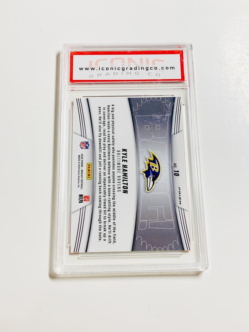 May include: A Kyle Hamilton Baltimore Ravens football card in a protective case. The card features a player image, team logo, and the number 10. The card is from the Prizm series and includes text about the player.