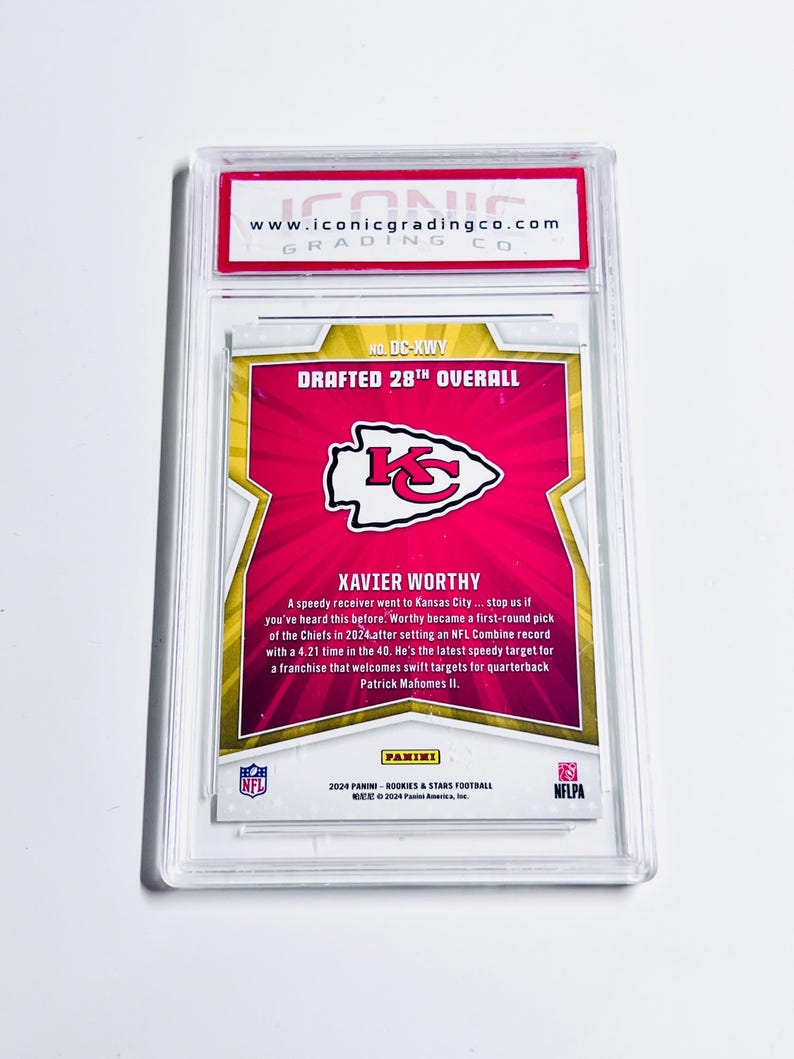 May include: A Panini football trading card featuring Xavier Worthy, drafted 28th overall. The card has a red and gold design with the Kansas City Chiefs logo. The card is encased in a clear protective holder.