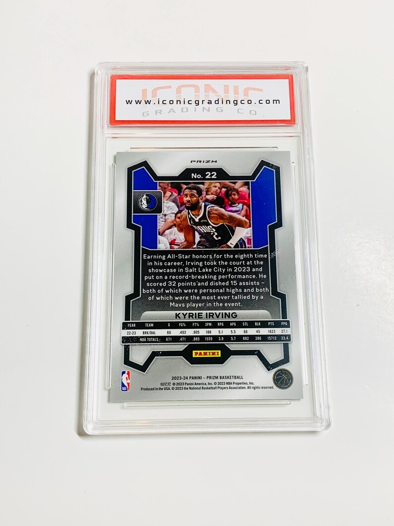 May include: A basketball trading card of Kyrie Irving, graded and encased in a protective holder. The card features a photo of Irving in action, with team and player statistics. The card is from the 2023-24 Panini Prizm Basketball series.