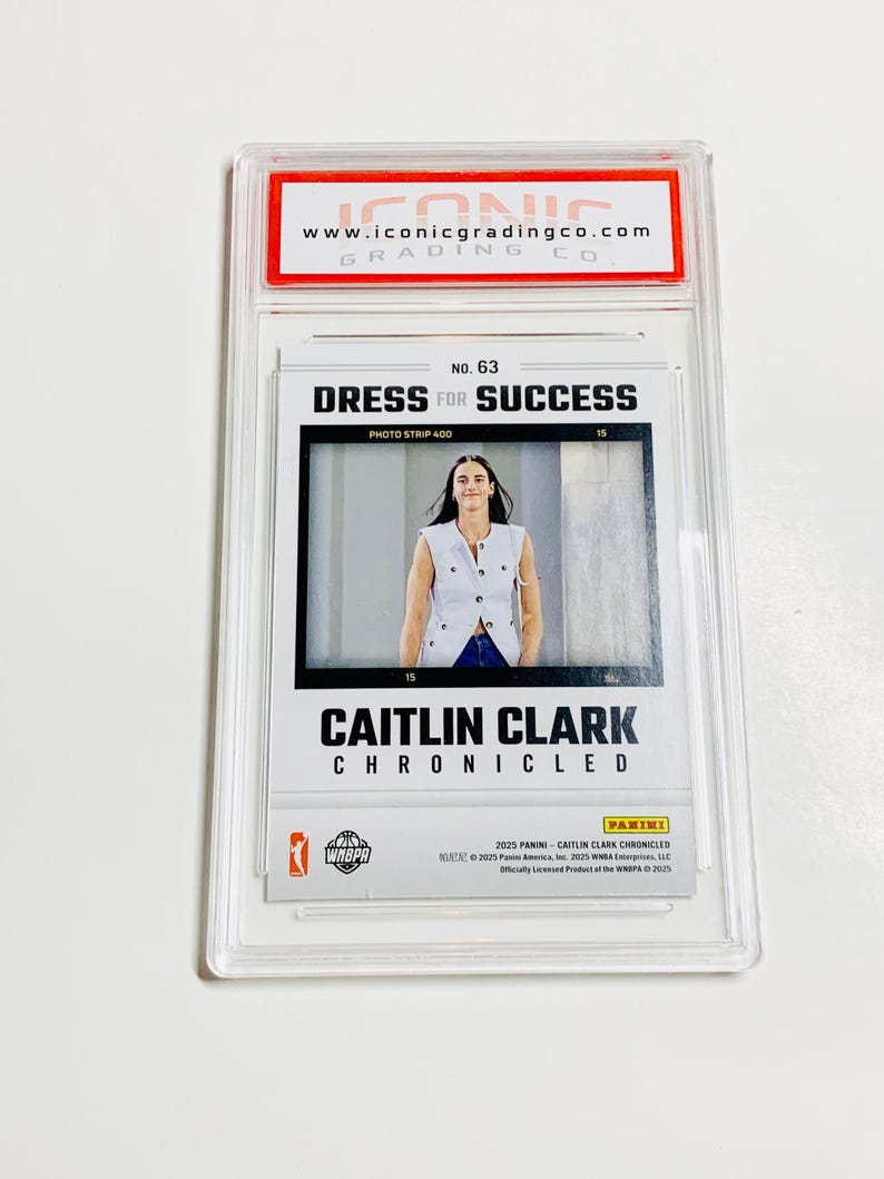 May include: A Caitlin Clark trading card, encased in a clear plastic holder. The card features a photo of Clark and the text "DRESS FOR SUCCESS" and "CAITLIN CLARK CHRONICLED". The top of the holder has the text "www.iconicgradingco.com".