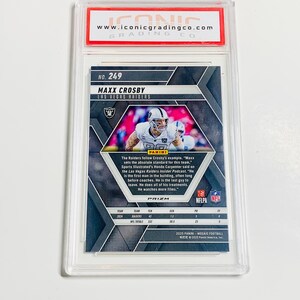 May include: A graded Maxx Crosby Las Vegas Raiders football card. The card is in a clear plastic case with a red and white Iconic Grading Co. label. The card features a photo of Crosby and the text "PRIZM".