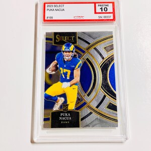 May include: A Puka Nacua football trading card from the 2023 Select series, graded Pristine 10. The card shows a player in a blue and yellow uniform. The card is encased in a clear protective holder.