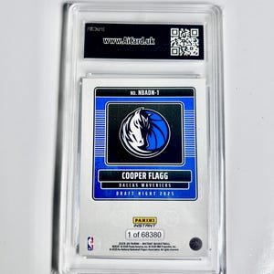 May include: A Cooper Flagg Dallas Mavericks Draft Night 2025 Panini Instant basketball card, encased in a protective holder. The card features a blue and white team logo and the text "www.AiCard.uk". The card is numbered 1 of 68380.