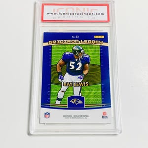May include: A Ray Lewis football trading card, graded and encased in a protective holder. The card features a player in a purple and black uniform with the number 52. The card is labeled "Gridiron Legacy" and includes the NFL and Panini logos.