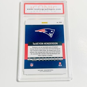 Pu&ograve; includere: Una carta di calcio di TreVeyon Henderson, valutata da Iconic Grading Co. La carta presenta un design blu e bianco con il logo dei New England Patriots e le statistiche del giocatore. La carta &egrave; racchiusa in un supporto protettivo trasparente.