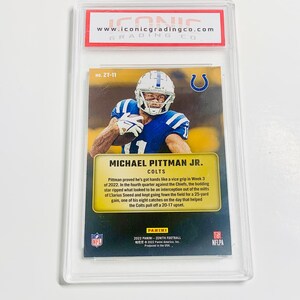 May include: A Michael Pittman Jr. Colts football card in a protective case. The card features a player in a blue and white uniform. The card is from the 2022 Panini Zenith Football series. The card is graded by Iconic Grading Co.
