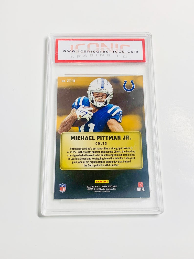 May include: A Michael Pittman Jr. Colts football card in a protective case. The card features a player in a blue and white uniform. The card is from the 2022 Panini Zenith Football series. The card is graded by Iconic Grading Co.