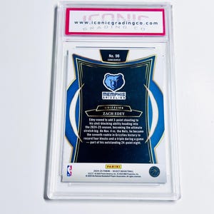 May include: A graded Zach Edey basketball card from the Memphis Grizzlies, encased in a clear protective holder. The card features the Grizzlies logo and player information. The top of the holder has a red and white label with the website address.