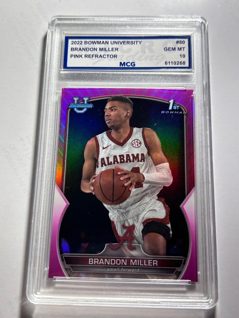 Op de afbeelding: Een roze refractor-verzamelkaart met een basketballer in een wit shirt met het woord "ALABAMA" op de voorkant. De speler houdt een basketbal vast en draagt een zwarte broek. De kaart is uit de serie 2022 Bowman University en is genummerd #80. De kaart is beoordeeld als GEM MT 10.
