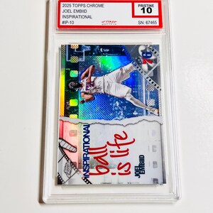Puede incluir: Una tarjeta coleccionable Joel Embiid Inspirational 2025 Topps Chrome, calificada como Pristine 10, en un estuche protector. La tarjeta muestra a un jugador de baloncesto en acci&oacute;n, con el texto "ball is life".