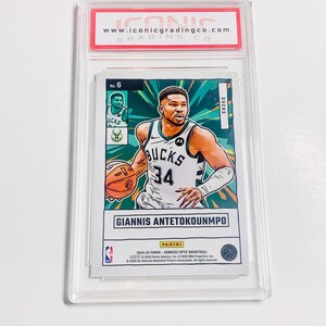 May include: A basketball trading card featuring Giannis Antetokounmpo in a Bucks uniform, number 34. The card is encased in a clear plastic holder with a red and white label from Iconic Grading Co. The card has a green and white background.