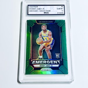 May include: A 2024 Prizm basketball card featuring Bronny James Jr. The card is graded GEM MT 10 and has a green prism design. The card features the text "EMERGENT" and "LOS ANGELES LAKERS".