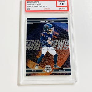May include: A graded Caleb Williams football card from the 2025 Masters series. The card features a player in a Chicago Bears uniform with the text "TOUCHDOWN MASTERS". The card is graded Pristine 10 and encased in a clear protective holder.