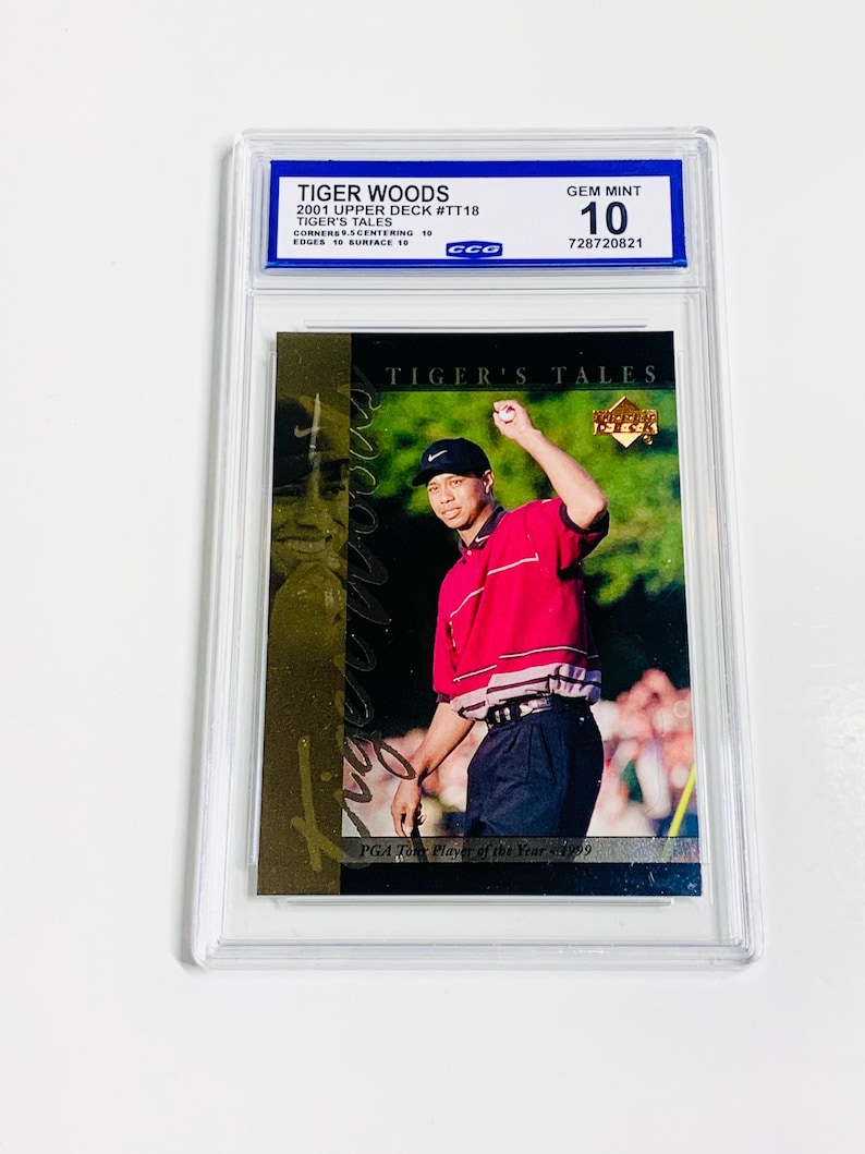 Pu&ograve; includere: Una carta collezionabile di Tiger Woods valutata del set Upper Deck 2001, con una foto di Woods con camicia rossa e pantaloni neri. La carta &egrave; valutata Gem Mint 10 da CCG, con il testo "TIGER'S TALES".