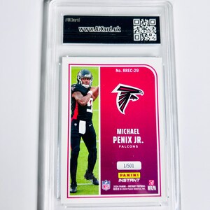 Puede incluir: Una tarjeta de f&uacute;tbol de Michael Penix Jr. calificada en una funda protectora. La tarjeta presenta una foto del jugador con el uniforme de los Falcons, con el logotipo del equipo y la informaci&oacute;n del jugador. La tarjeta est&aacute; etiquetada como "1/501".