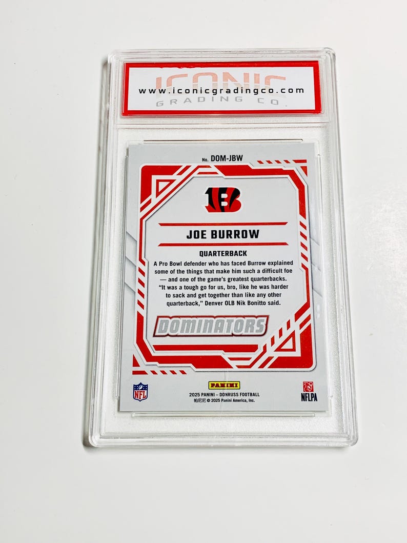 Może przedstawiać: Karta do gry w futbol amerykański z Joe Burrow w przezroczystym plastikowym etui. Karta ma czerwono-biały wz&oacute;r z napisem "JOE BURROW QUARTERBACK" i logo drużyny. Pochodzi z serii 2025 Panini Donruss Football.