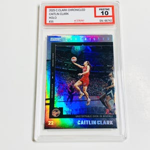 May include: A Caitlin Clark basketball card from the 2025 C.Clark Chronicled series, graded Pristine 10. The card features a holographic image of Clark in action for the Indiana Fever. The card is encased in a protective holder.