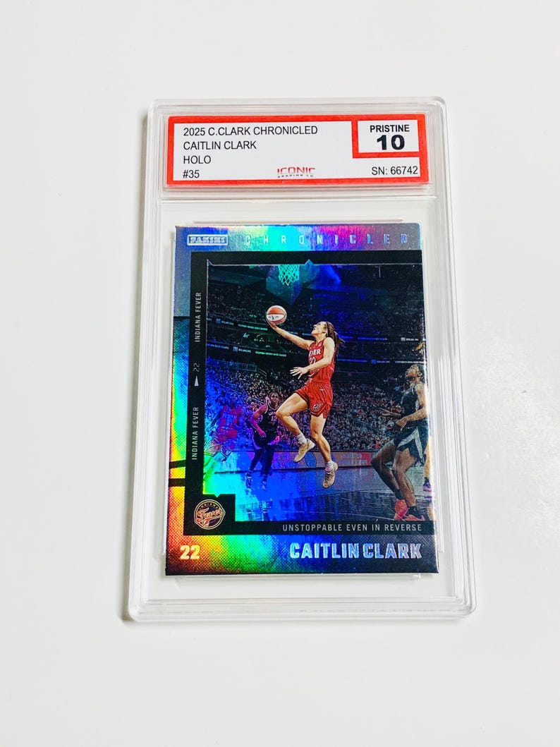 May include: A Caitlin Clark basketball card from the 2025 C.Clark Chronicled series, graded Pristine 10. The card features a holographic image of Clark in action for the Indiana Fever. The card is encased in a protective holder.