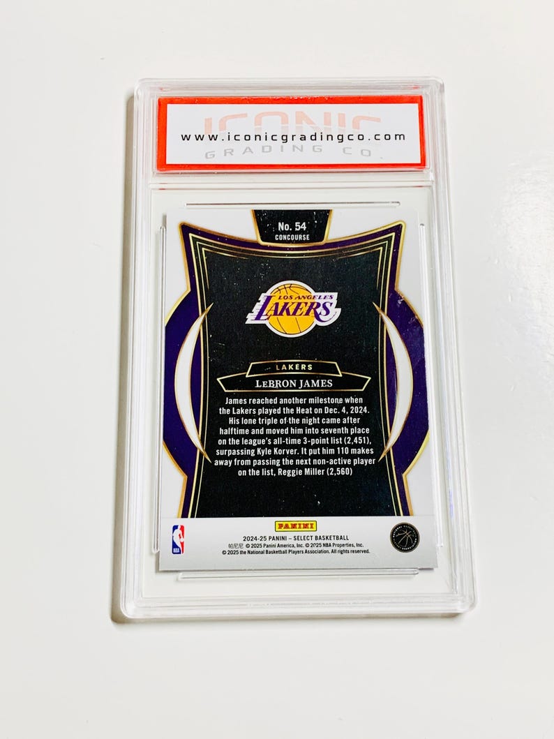 May include: A basketball trading card encased in a clear plastic holder. The card features the Los Angeles Lakers logo and text that reads "LEBRON JAMES." The card is graded by Iconic Grading Co.