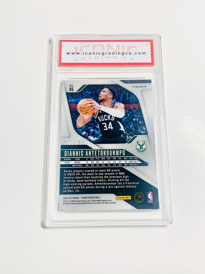 May include: A basketball trading card featuring Giannis Antetokounmpo in a Bucks uniform. The card is graded and encased in a protective holder. The card's details include player stats, the Prizm logo, and the Panini logo.