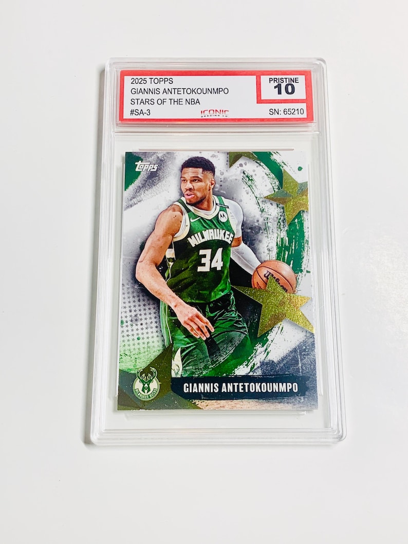 May include: A 2025 Topps basketball card featuring Giannis Antetokounmpo in a Milwaukee Bucks uniform. The card is graded Pristine 10 and encased in a protective holder. The card's text includes "STARS OF THE NBA" and "#SA-3".