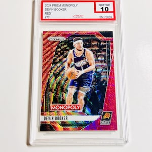 Pu&ograve; includere: Una carta collezionabile rossa e iridescente 2024 Prizm Monopoly Devin Booker, valutata Pristine 10, racchiusa in un supporto protettivo trasparente. La carta presenta un'immagine del giocatore e il testo "MONOPOLY" e "Suns".