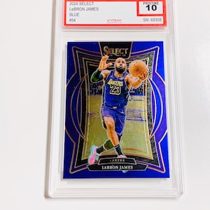 May include: A blue 2024 Select LeBron James basketball card, graded Pristine 10, encased in a protective holder. The card features LeBron James in a Lakers uniform, with gold accents and the Lakers logo.