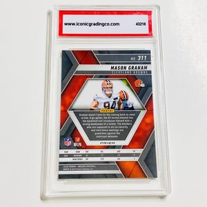 Op de afbeelding: Een voetbal trading card met Mason Graham van de Cleveland Browns. De kaart, met nummer 311, zit in een transparante plastic houder. De houder heeft een rood-wit label van iconicgradingco.com.