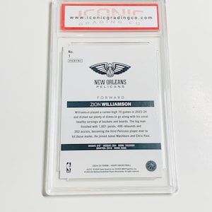 May include: A Zion Williamson basketball card, graded and encased in a clear plastic holder. The card features the New Orleans Pelicans logo and player information, including height, weight, and draft details. The top of the holder reads "www.iconicgradingco.com".