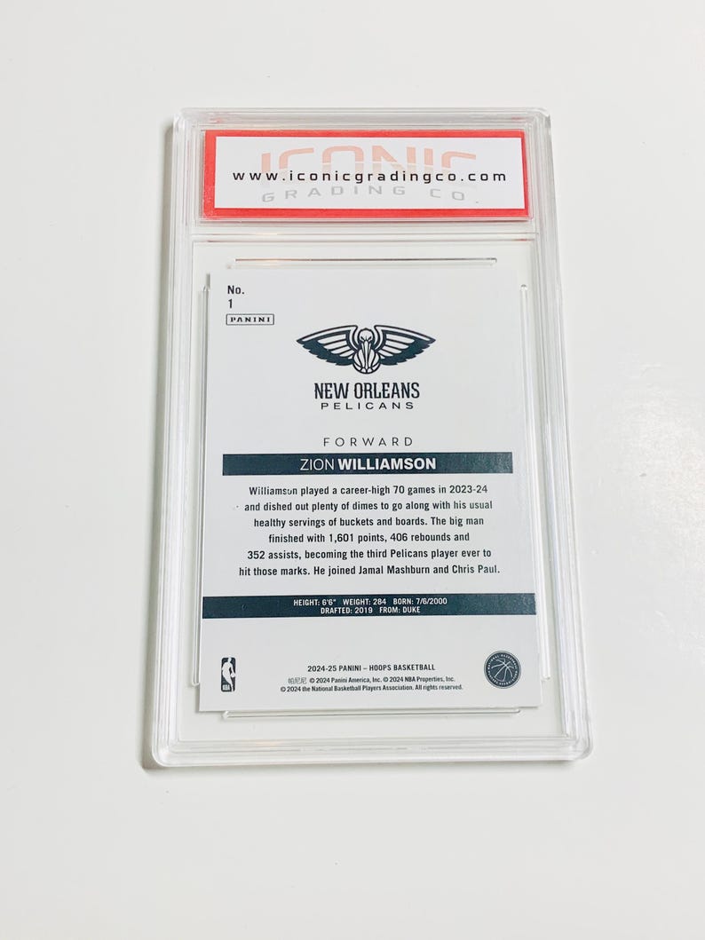 May include: A Zion Williamson basketball card, graded and encased in a clear plastic holder. The card features the New Orleans Pelicans logo and player information, including height, weight, and draft details. The top of the holder reads "www.iconicgradingco.com".