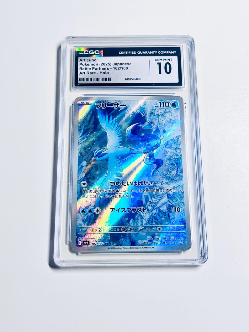 Op de afbeelding: Een beoordeelde Articuno Pok&eacute;mon-kaart in een beschermende hoes. De kaart heeft een holografisch ontwerp met blauwe en witte tinten en Japanse tekst. De hoes is door CGC gelabeld met "GEM MINT 10".