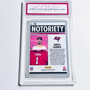 Pode incluir: Um cart&atilde;o de negocia&ccedil;&atilde;o esportivo classificado e embalado em um suporte de pl&aacute;stico transparente. O cart&atilde;o apresenta Emeka Egbuka em uma camisa vermelha e branca. O cart&atilde;o tem o texto "NOTORIETY" e "EGBUKA". &Eacute; da s&eacute;rie 2025 Panini Mosaic Football.