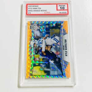 May include: A football trading card featuring Kyle Hamilton in a mosaic design. The card is graded Pristine 10 and includes the text "2025 MOSAIC KYLE HAMILTON BANG-ORANGE MOSAIC #10". The card is encased in a clear protective holder.