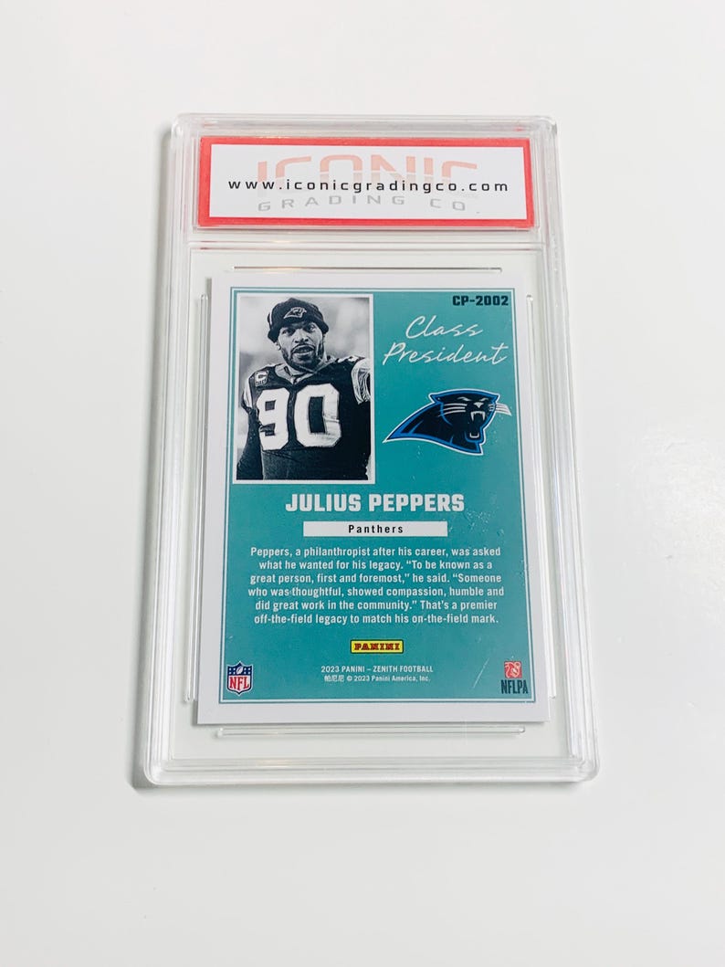 May include: A football trading card featuring Julius Peppers of the Carolina Panthers. The card is encased in a protective holder and includes the text "Class President" and the Panini logo. The card has a teal and black color scheme.