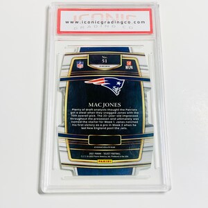 May include: A graded Mac Jones football card from the 2021 Panini Select Football series. The card is encased in a clear plastic holder with a red and white label from Iconic Grading Co. The card features the NFL and NFLPA logos.