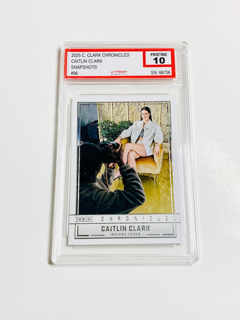 May include: A Caitlin Clark trading card, graded Pristine 10, in a clear protective case. The card shows a photo of Caitlin Clark and the text "2025 C. Clark Chronicled Snapshots #96". The card is from the Indiana Fever.