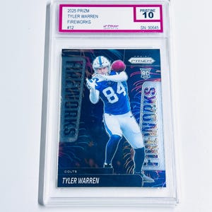 Puede incluir: Una tarjeta de f&uacute;tbol con Tyler Warren en uniforme azul y blanco, atrapando un bal&oacute;n rosa. La tarjeta est&aacute; etiquetada como "2025 Prizm Fireworks" y est&aacute; calificada como "Pristine 10". La tarjeta est&aacute; dentro de un soporte protector transparente.