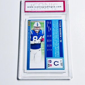 Puede incluir: Una tarjeta de f&uacute;tbol de Tyler Warren, TE, en un estuche protector. La tarjeta presenta una foto del jugador con uniforme azul y blanco. La tarjeta es de la serie 2024 Panini Donruss Football. El estuche tiene una etiqueta roja y blanca.