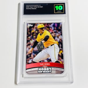 May include: A graded baseball card featuring Paul Skenes in a yellow and black Pittsburgh Pirates uniform. The card is encased in a clear plastic holder with a grade of 10. The card's text includes "2025 Topps Hobby Rip Night" and "Pittsburgh Pirates."