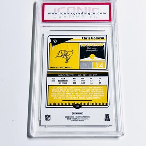 May include: A Chris Godwin football trading card, graded by Iconic Grading Co. The card features a Tampa Bay Buccaneers logo and player statistics. The card is encased in a clear protective holder.