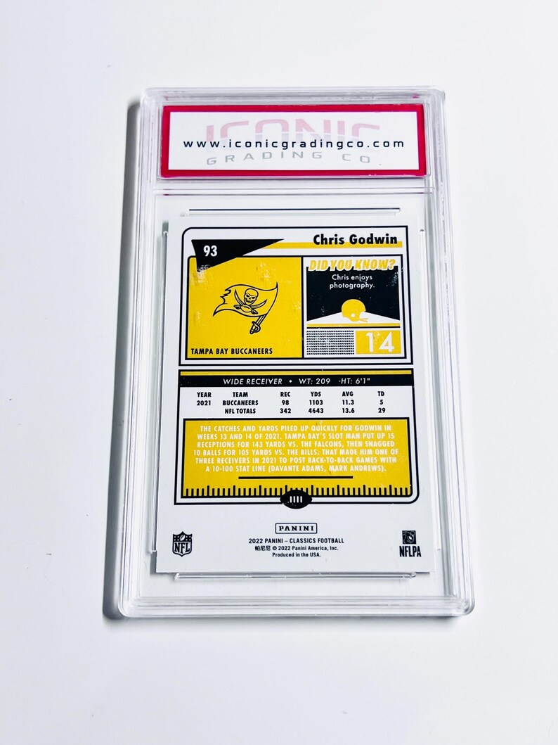 May include: A Chris Godwin football trading card, graded by Iconic Grading Co. The card features a Tampa Bay Buccaneers logo and player statistics. The card is encased in a clear protective holder.