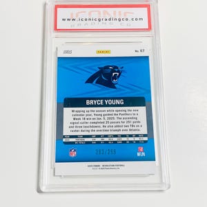 May include: A graded Bryce Young football card from the 2025 Panini Revolution series. The card features a blue and black Carolina Panthers logo and player statistics. The card is encased in a clear protective holder.