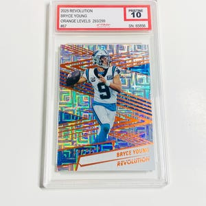 May include: A graded trading card featuring Bryce Young in a Carolina Panthers uniform. The card is from the 2025 Revolution series, Orange Levels 293/299, and is graded Pristine 10. The card has a serial number of 65856.