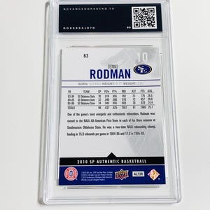 May include: A Dennis Rodman basketball card from the 2010 SP Authentic series, encased in a protective holder. The card features Rodman's name, statistics, and a brief biography. The card is graded by Advanced Grading.